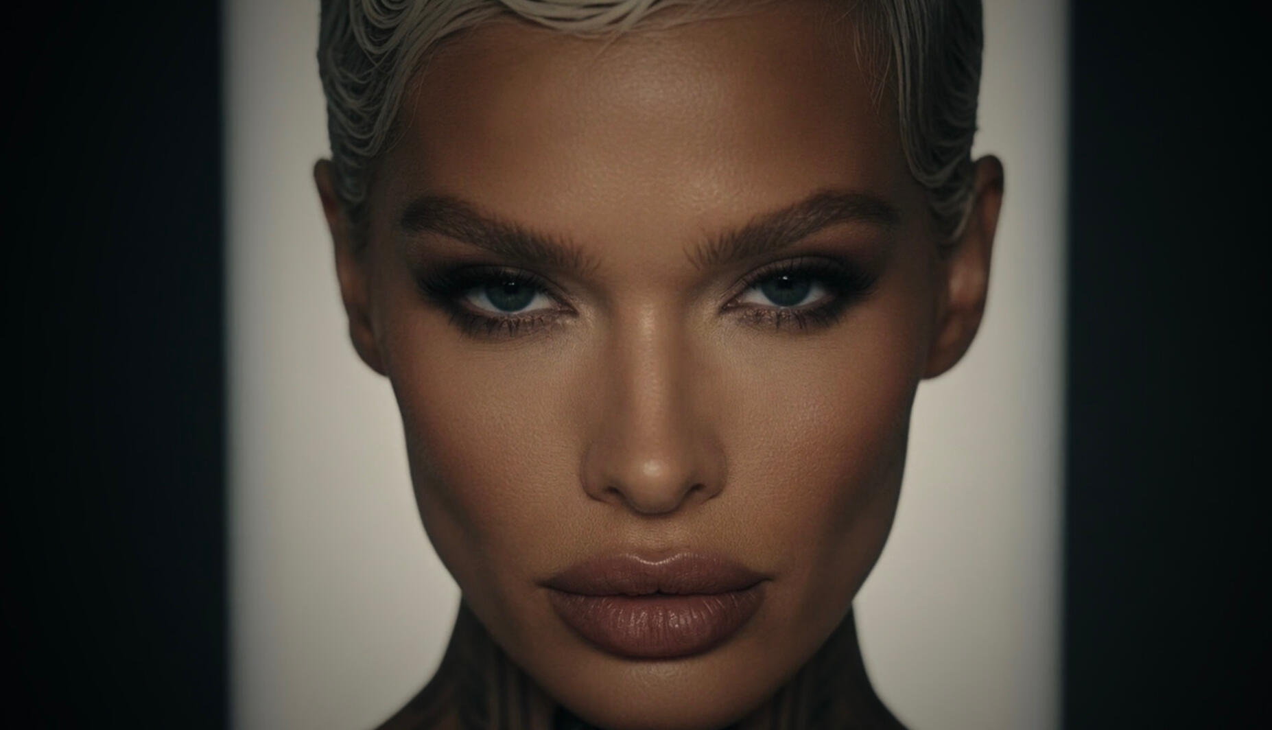 Mia Liorvian | Liorvian Portfolio Detail: Seduction in Silver Close-up photographic portrait focusing on Mia Liorvian face. Features include detailed feathered brows, deep-set smoky eyes, defined lips, and short platinum-silver hair with a wet finish, split by dramatic shadows and highlight. Liorvian Studios.